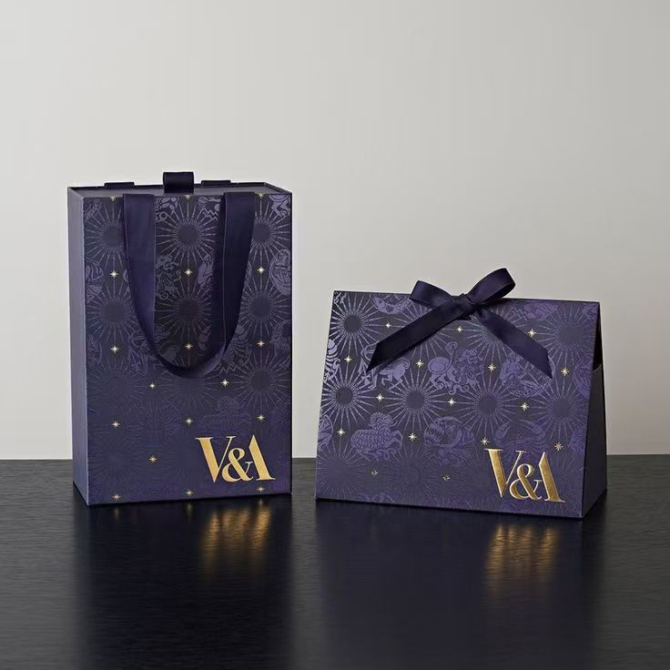 V&A 联名藏蓝星纹纸袋与礼盒,金色烫印,置于深色台面